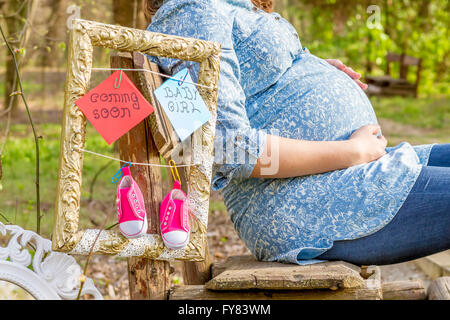 Pregnant woman outdoor in the park on bench close up. Stock Photo