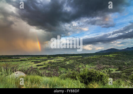 A passing storm leaves a rainbow over the foothills of the Rocky Mountains at Cheyenne Mountain State Park near Colorado Springs Stock Photo