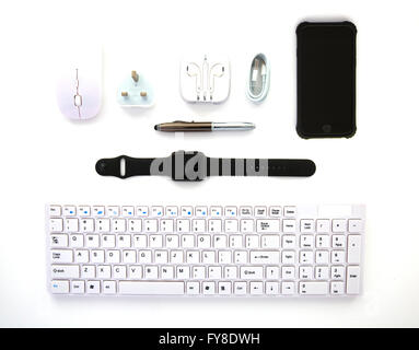 White Keyboard, Mouse, iPhone, Pen, Charger, USB Lead and Earphones on a white background overhead view Stock Photo