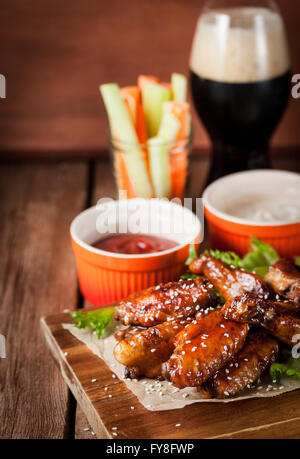 Spicy hot chicken wings cooked with honey and soy,  topped with sesame seeds, served with sauce Stock Photo