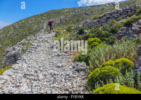 Lone female walker on Italian Road footpath, Kalymnos, Greece Stock Photo