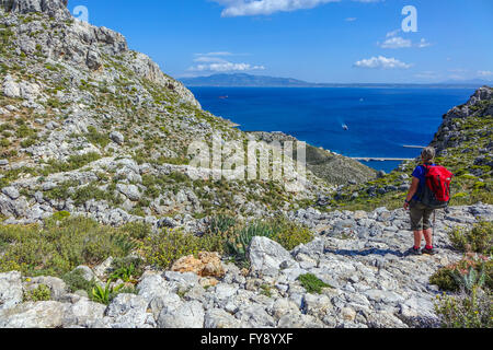 Lone female walker on Italian Road footpath, Kalymnos, Greece Stock Photo