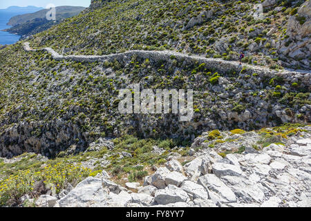 Lone female walker on Italian Road footpath, Kalymnos, Greece Stock Photo