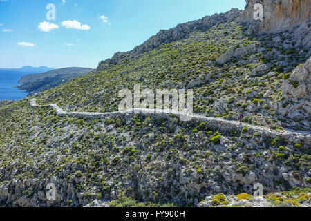 Lone female walker on Italian Road footpath, Kalymnos, Greece Stock Photo