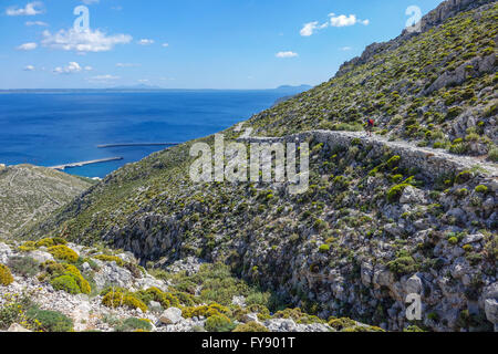 Lone female walker on Italian Road footpath, Kalymnos, Greece Stock Photo