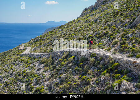 Lone female walker on Italian Road footpath, Kalymnos, Greece Stock Photo