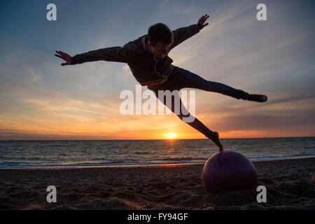 Aberystwyth Wales UK, Saturday 23 April 2016 UK weather: As the sun sets over Cardigan Bay in Aberystwyth at the end of a day of sunshine but cold northerly winds, teenager STACY WARREN, on a weekend break from Birmingham, performs acrobatic leaps in the air off the beach. photo Credit:  Keith Morris/Alamy Live News Stock Photo