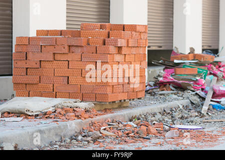 New bricks are stacked on a pallet stand at the trade pavilions around construction debris Stock Photo