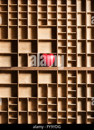 Red heart in empty wooden box with many compartments Stock Photo