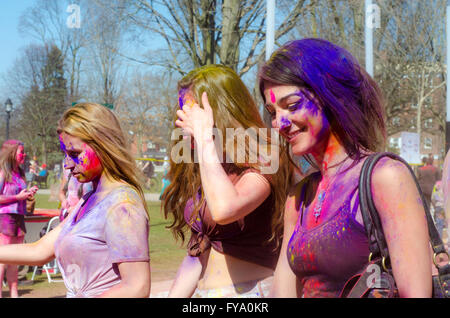 Portrait of three unidentified young girls with a background of people having fun and celebrating Holi festival Stock Photo