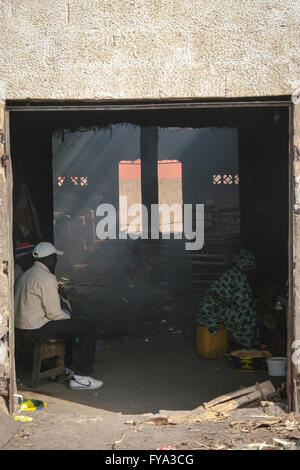 African man at a smoked fish warehouse factory Tanjih fish market, the biggest African fish market, Gambia, Africa Stock Photo