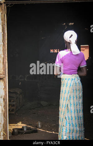 African woman at a smoked fish warehouse factory Tanjih fish market, the biggest African fish market, Gambia, Africa Stock Photo