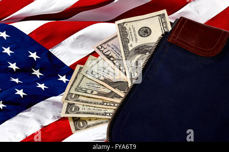 Money bag containing US Currency including a hundred dollar bill, a fifty, two twenties and three ones on an American flag Stock Photo