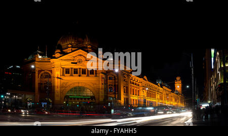 A photo of Flinders street station with lines of lights from moving cars at night. Stock Photo