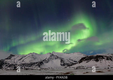 Northern Lights / Aurora borealis, weather phenomenon showing light display over the snow covered mountains in winter, Iceland Stock Photo