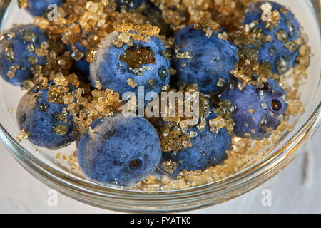 Blueberries and brown sugar in a glass bowl on a white table Stock Photo