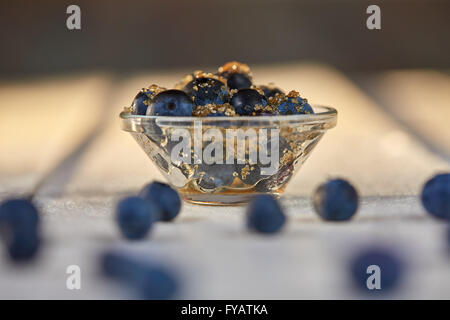 Blueberries and brown sugar in a glass bowl on a white table Stock Photo