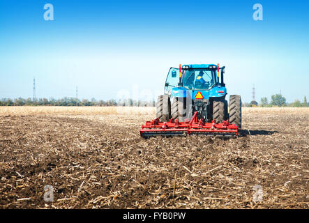 Blue tractor in the field on a sunny day Stock Photo