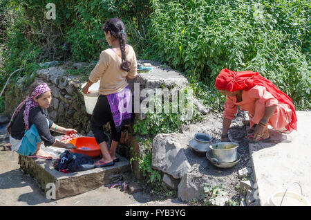 Three women washing clothes and dishes on footpath,  village near McLeod Ganj, Dharamshala, Kangra Distict, Himachal Pradesh, In Stock Photo