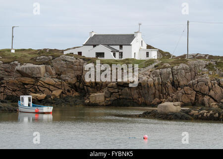 House and fishing boat Ireland at The Rosses near Burtonport County Donegal, Ireland. The house is either on Inishcoo, or Eighter Island. Stock Photo