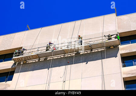 People in a suspended scaffold or swing stage cleaning and restoring the side of a building in Nashville, TN Stock Photo