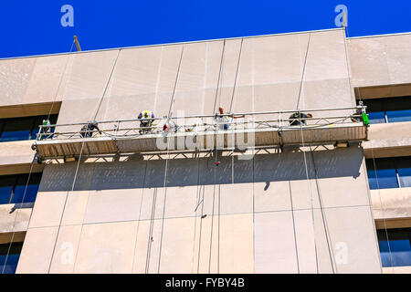 People in a suspended scaffold or swing stage cleaning and restoring the side of a building in Nashville, TN Stock Photo