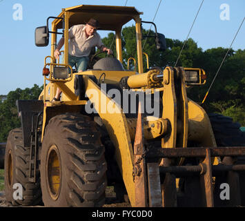 A mature guy and his big yellow construction machine, April 2016. Stock Photo
