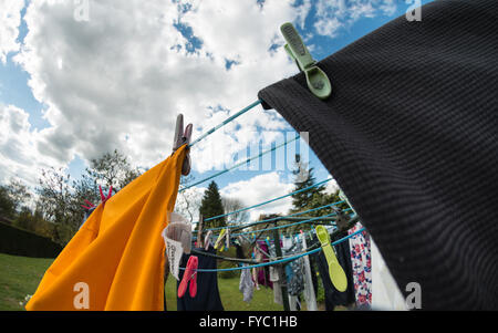 washing hanging out to dry on bright sunny day crumpled vest in foreground held by peg Stock Photo