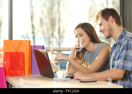 Couple of shoppers with shopping bags buying online and choosing products in a coffee shop Stock Photo