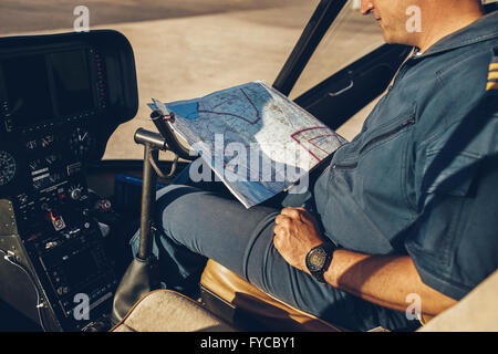 Close up shot of a helicopter pilot reading map while sitting in the cockpit of the aircraft. Stock Photo