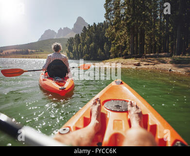 Couple canoeing in the lake on a summer day. Man and woman in two different kayaks in the lake on a sunny day. Stock Photo