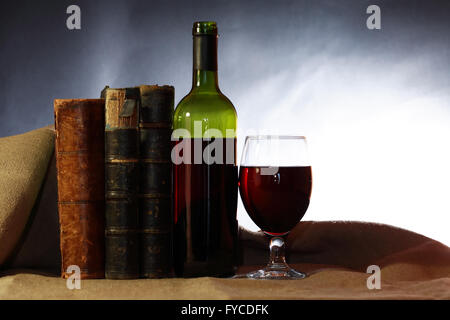 In vino veritas. Red wine near old books on dark background Stock Photo