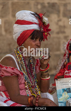 A Cuban lady dressed in traditional costume smokes a cigar Stock Photo