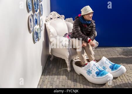 Tourist poses with Delft Blue clogs at Keukenhof, one of the world's famous flower gardens, Lisse, South Holland, Netherlands. Stock Photo