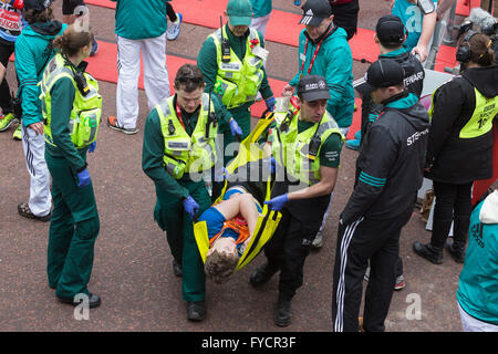 London, UK. 24 April 2016. Medics from St John Ambulance help a runner who collapsed after crossing the finish line.The 2016 Virgin Money London Marathon finishes on the Mall, London, United Kingdom. Stock Photo