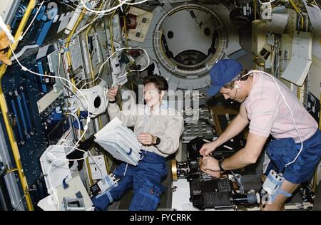 NASA astronaut Stephen Oswald, right, changes a film magazine on the IMAX camera as Canadian astronaut Roberta Bondar works at the International Microgravity Laboratory's biorack aboard the Space Shuttle Discovery mission STS-42 January 23, 1992 in Earth Orbit. Stock Photo