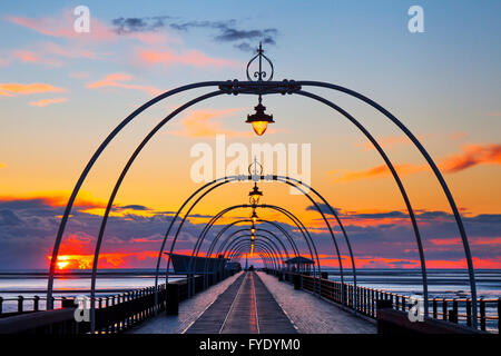 Southport Pier, Merseyside, UK. 26th April, 2016. UK Weather. Sunset over the Irish Sea as seen from Southport seafront looking out over the pier and the extensive sands of the resort exposed at low water. Credit:  Mar Photographics/Alamy Live News Stock Photo