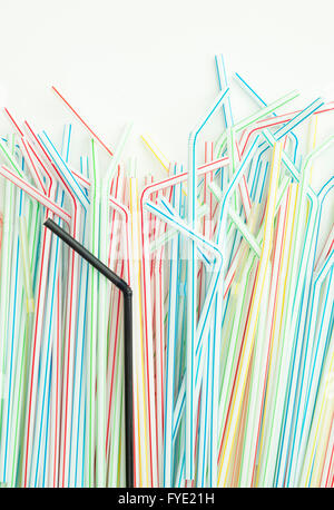 Detail of single black drinking straw into a group of colorful drinking straws  with isolated background Stock Photo