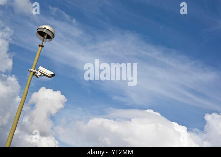 Security camera placed outdoors with bluy sky and clouds at the background Stock Photo