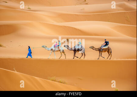 ERG CHEBBY, MOROCCO - April, 12, 2013: Tourists riding camels in Erg Chebbi, Morocco Stock Photo