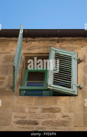 Peeling paint on a green shutters on a stone french house in the Dordogne region of France Stock Photo