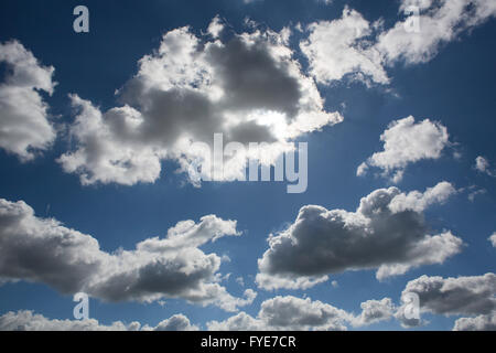 Large clouds are lit from behind by the incredibley bright sun in a deep blue sky. Stock Photo