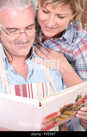 Smiling man and woman selecting recipe on a cookbook Stock Photo