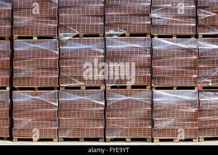 Many new bricks on foiled pallets, stacked on one another and ready for transport and use. Stock Photo