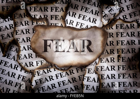 Burnt Fear. Burnt pieces of paper with the word Fear. Close-up. Stock Photo