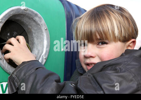 Little boy throwing a glass bottle in a container Stock Photo