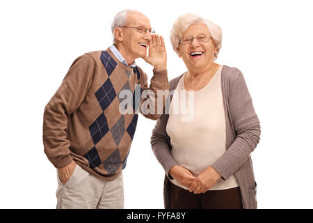 Studio shot of an old man whispering something to his wife isolated on white background Stock Photo