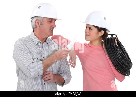 electricians talking and holding a bulb and a wire Stock Photo