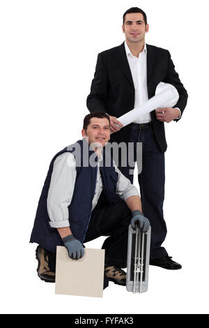 Portrait of an engineer and a workman holding a tile and a ceramic tile cutter Stock Photo
