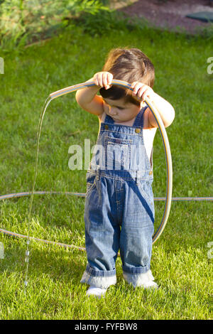 little baby boy gardener playing in his front yard with the hose Stock Photo